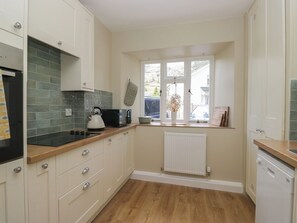 A kitchen with white cabinets, a black kettle, a toaster, and a window with a view of the outside. - The Barn at Grasmere (Ambleside)
