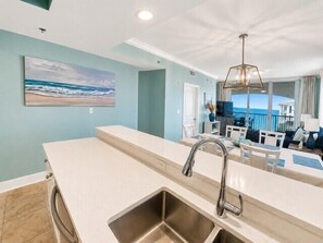 A modern kitchen with a large island, a built-in sink, and a view of the ocean. - Azure Resort Luxury, Exceptional Value (Fort Walton Beach)