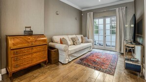 Ein Wohnzimmer mit einem hölzernen Kommode, einem Sofa, einem Fernseher und einem großen Fenster.