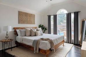 Embracing luxury and comfort in this spacious bedroom, where a king-size bed beckons amidst plush cushions. While glass window reveals a breathtaking view of the backyard pool area, creating a perfect blend of comfort and serenity. - Frisco Pool Retreat | BBQ, Hot Tub & Shuffleboard (Frisco)