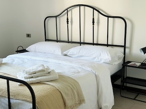 A bed with a black metal frame, white bedding, and a beige throw blanket. - Apartment with patio a stone's throw from the lake (Colico)