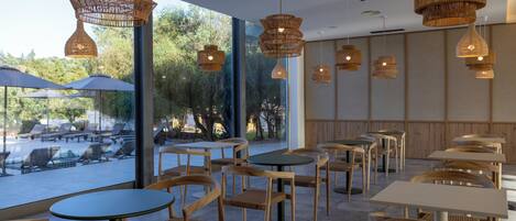 Un caffè all'aperto con mobili in vimini, tavoli rotondi e lampade pendenti in vimini.