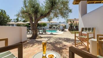A poolside area with a table, a glass of beer, and a bowl of snacks.