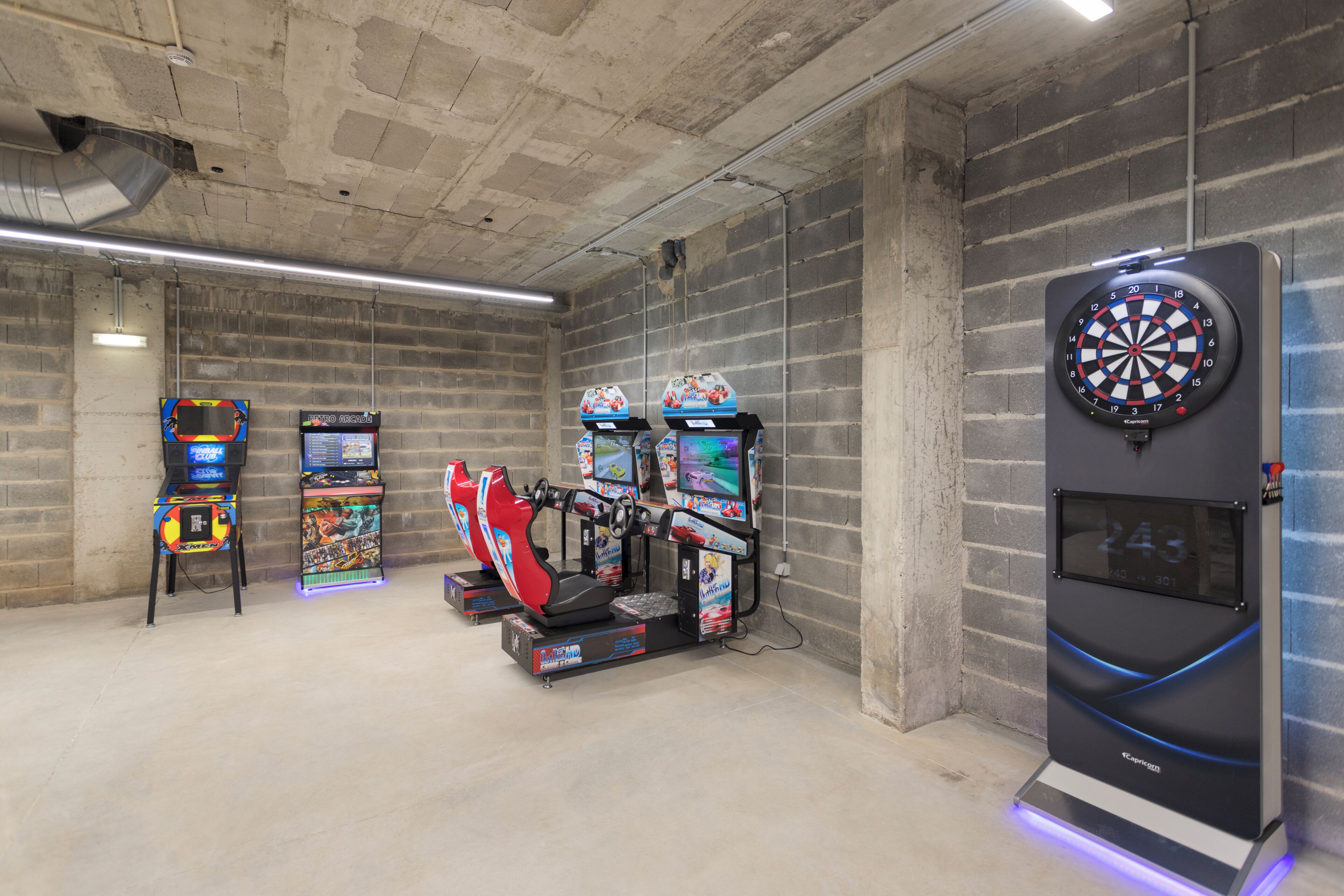 Een speelruimte met zitmachines, een dartbord en een race simulator.