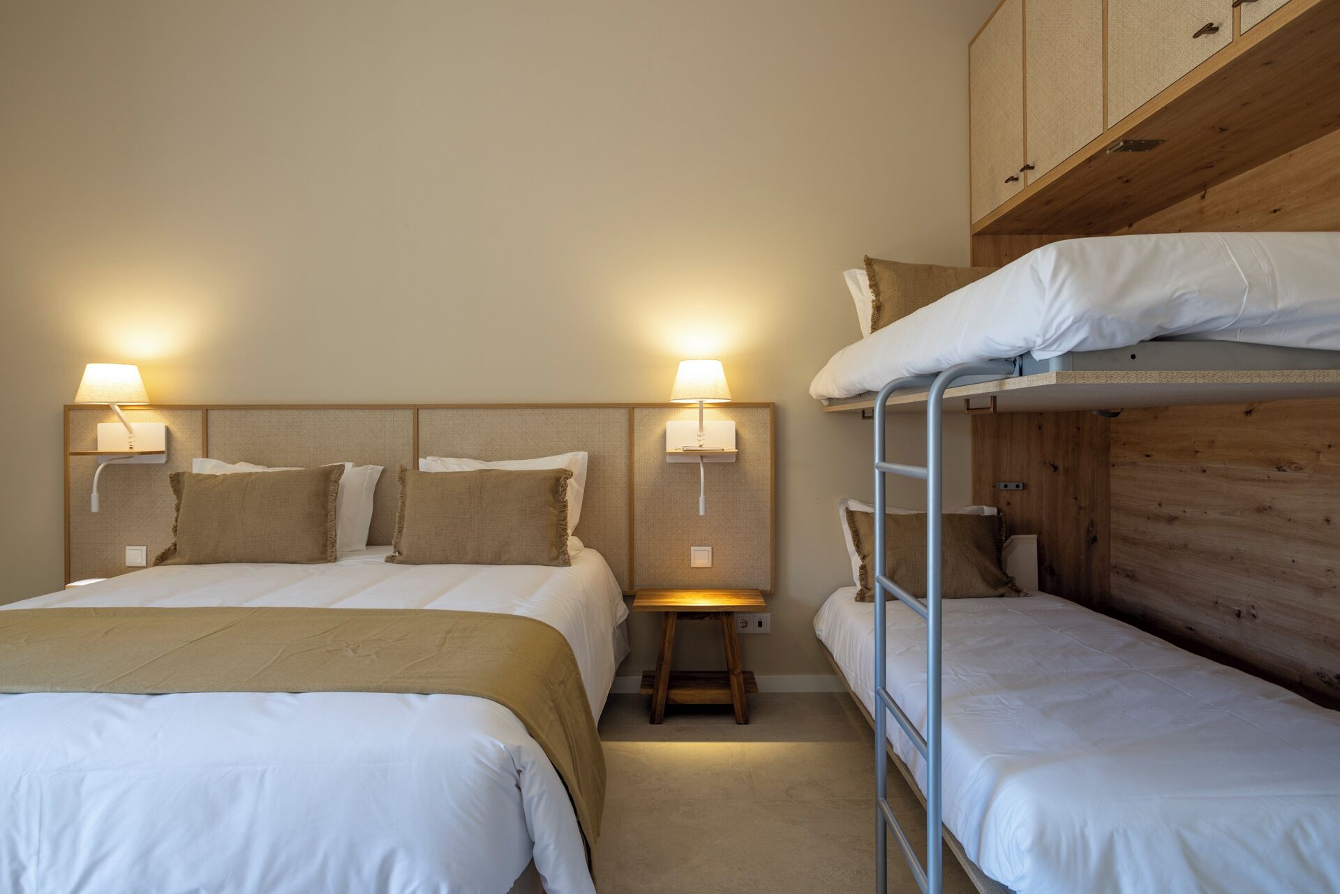 Una stanza con un letto a castello, un letto singolo e due lampade da comodino.