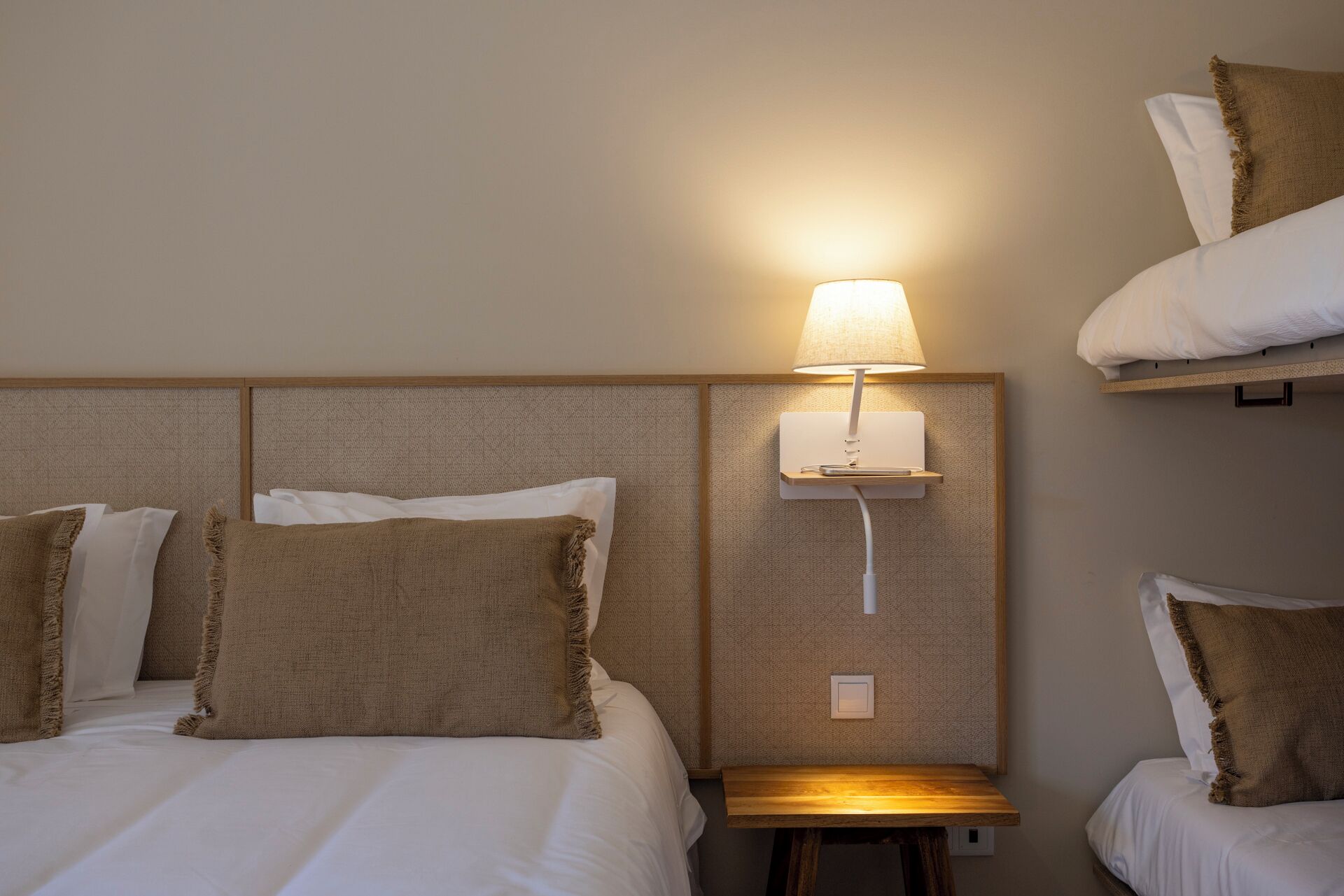 Una habitación de hotel con una cama, una mesita de noche, una lámpara y una estantería en la pared.