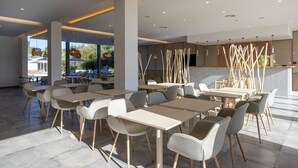 En modern restaurang med bord och stolar placerade i en rymlig och välplanerad miljö, stora fönster med fin utsikt och en stilren, samtida design.