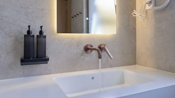 A modern bathroom with a white sink, two faucets, and a mirror above.