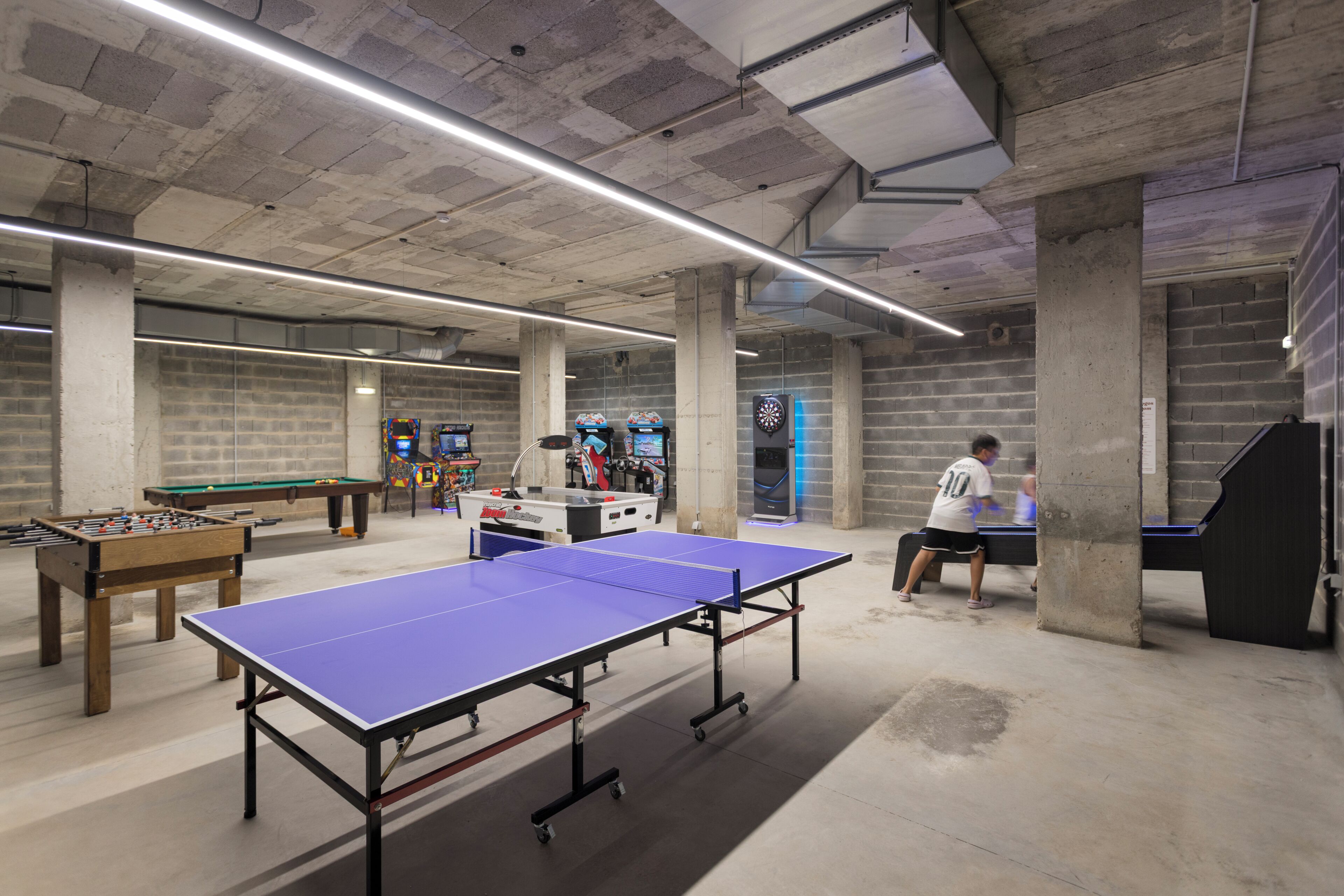 A recreational area with a foosball table, ping pong table, and dartboards.
