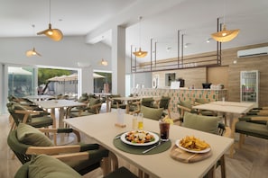 Un restaurant moderne avec des tables et des chaises hautes, un espace buffet et une vue sur l’extérieur.