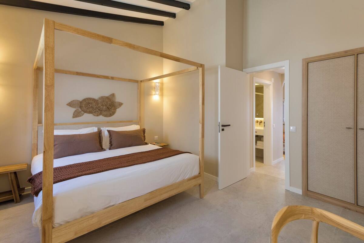 Un dormitorio con una cama con dosel, un armario de madera y una pequeña silla de madera.