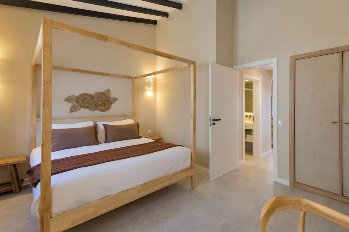 Ein Schlafzimmer mit Himmelbett, Holzschrank und kleinem Holzstuhl.