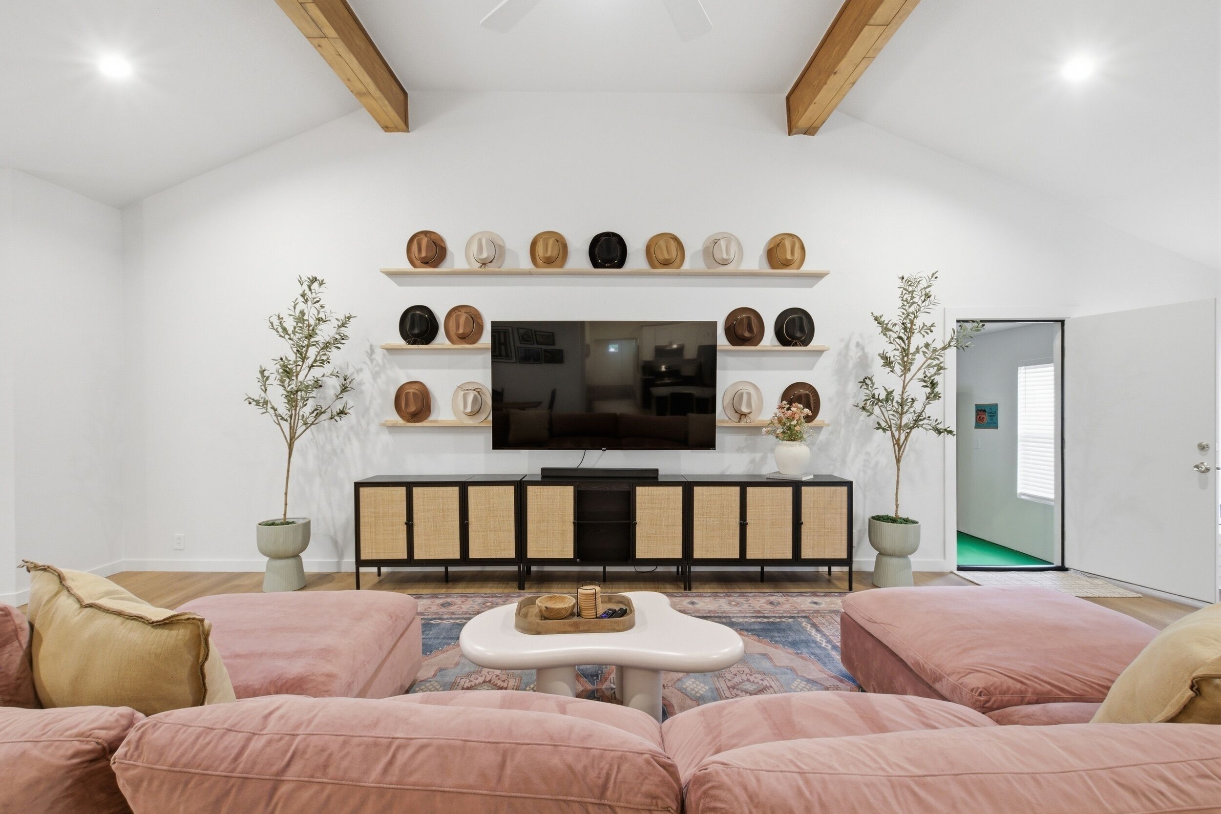 Una sala de estar con televisor, sofás, una mesa de centro y un perchero de pared.