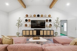 A living room with a TV, sofas, a coffee table, and a wall-mounted hat display. - Arlington Home Walk to AT&T w Game Room & Fire Pit (Arlington)