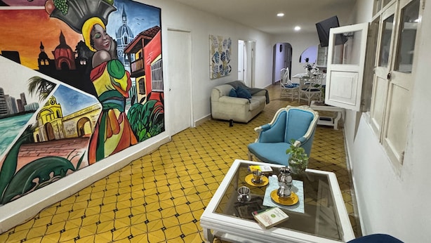 Ein Zimmer mit Fliesenboden, einer Couch, einem Couchtisch und einem Wandgemälde.
