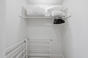 Een witte kast met planken, een kledingroede en een radiator.