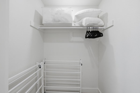 A white closet with shelves, a hanging rack, and a radiator. - Family Getaway Near Toyota Stadium w BBQ & Hot Tub (Frisco)