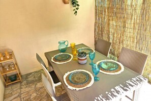Een eettafel met geweven tafelonderleggers, glaswerk en een karaf.
