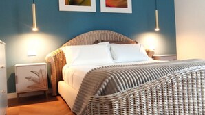 Ein Schlafzimmer mit einem Rattan-Kopfstück, weißer Bettwäsche und zwei Wandleuchten.
