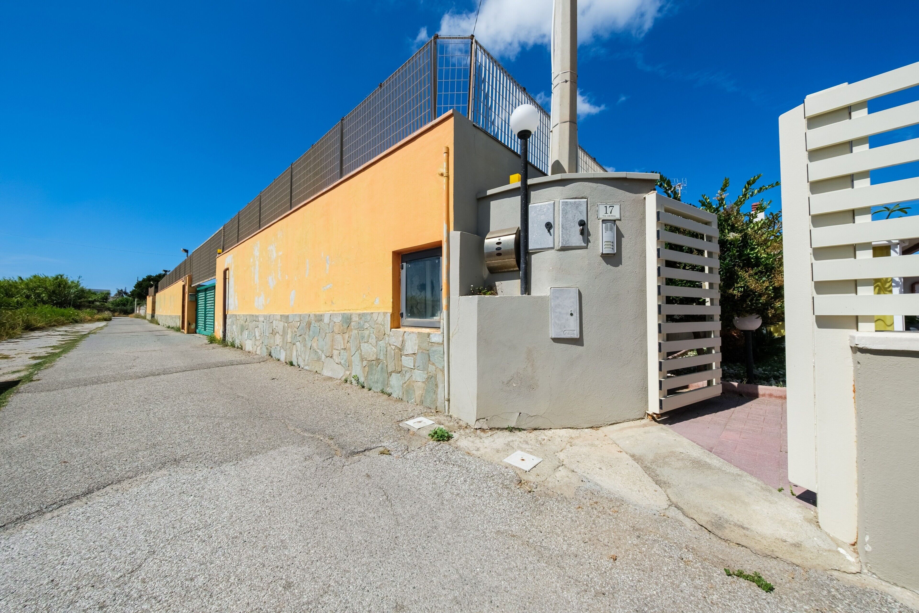 Un bâtiment à la façade jaune, doté d’un socle en pierre et d’une structure métallique sur laquelle sont installés des panneaux solaires.