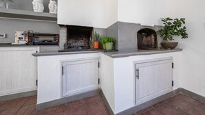 Una cocina con armarios blancos, horno empotrado, cafetera y plantas en macetas.