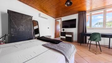A bedroom with a bed, a map cabinet, a desk, a chair, and a TV.