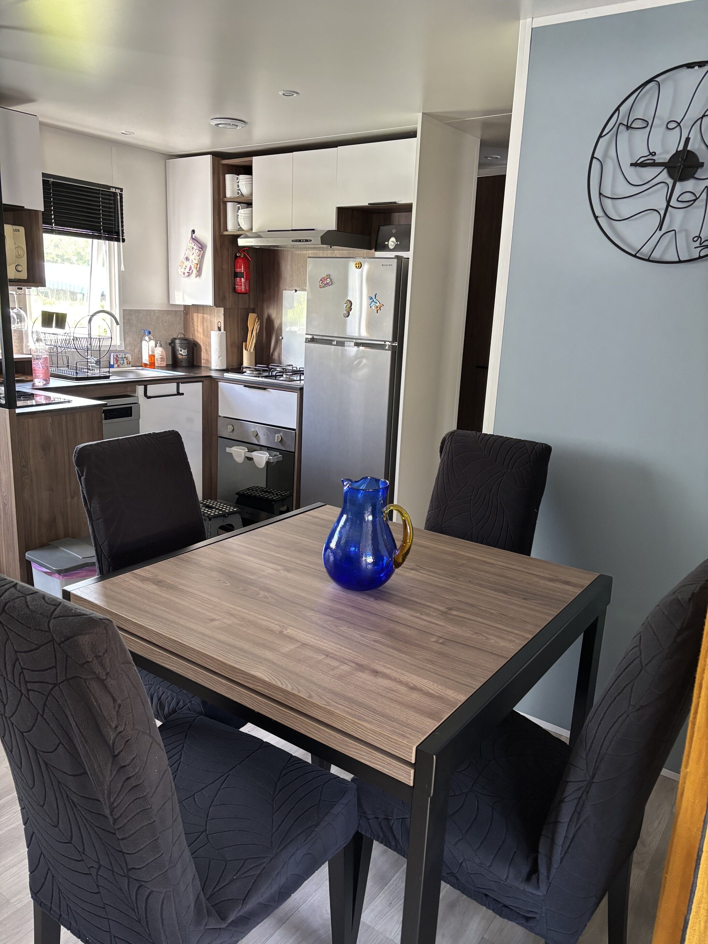 A modern kitchen with a dining table, chairs, and a blue vase.