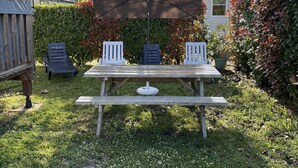 Une table de pique-nique en bois, dotée d’un auvent, ainsi que deux chaises blanches et une petite table.