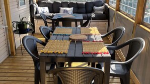 Un espace extérieur aménagé, abrité, avec une table et des chaises, un canapé et une vue par une fenêtre.