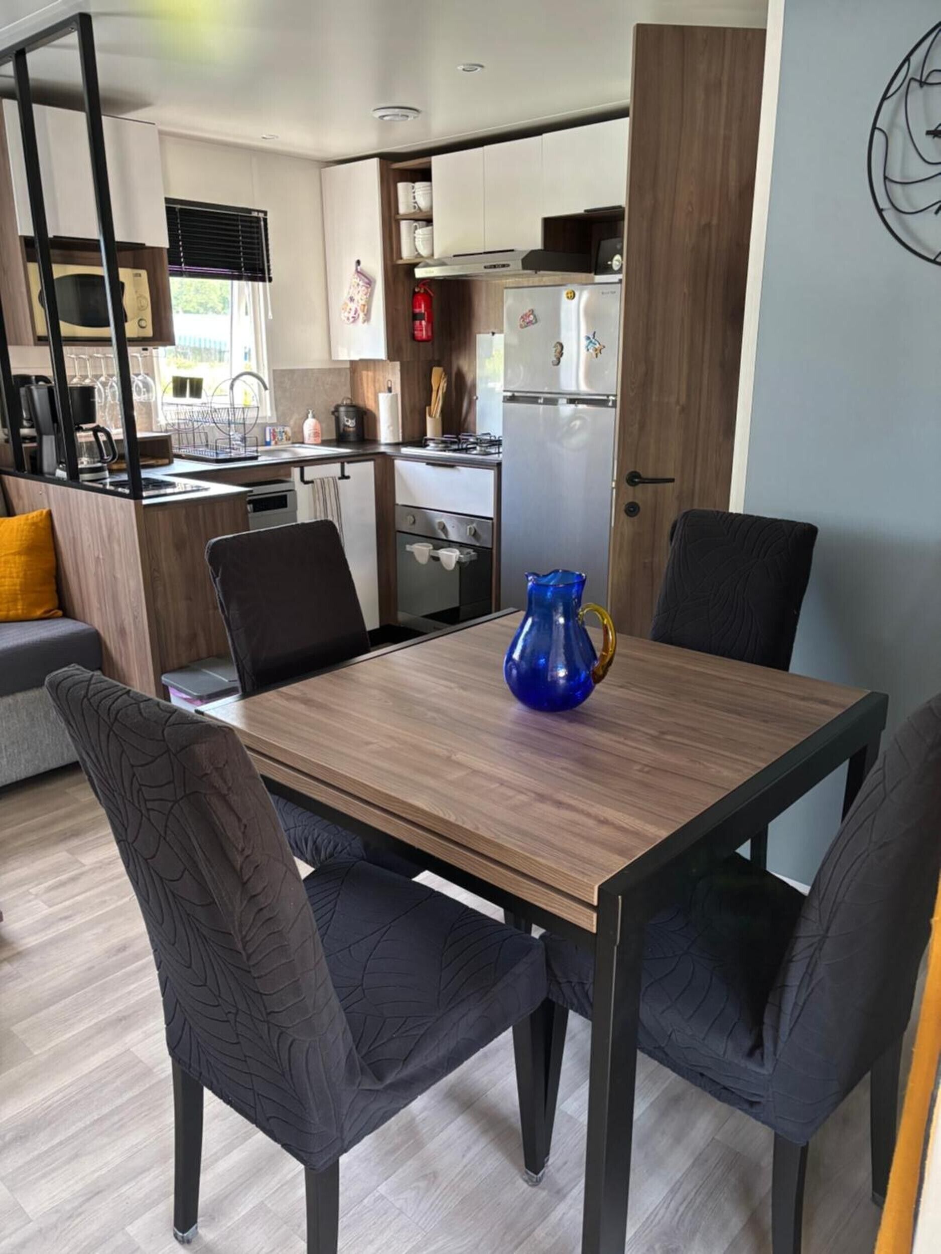 Une cuisine compacte avec un coin repas, comprenant une table avec quatre chaises, un vase bleu et un four à micro-ondes.