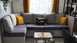 Un salon moderne avec un canapé d’angle gris, une petite table basse en bois et un fauteuil noir.