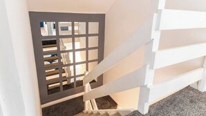 Un escalier avec une rampe blanche et une cloison grise.