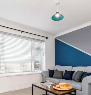 Uma sala de estar moderna com um sofá, uma mesa de centro e um lustre.