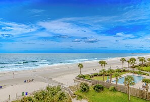 A beach view with a pool and palm trees. - Oceanfront Condo with Sunset Views (Myrtle Beach)
