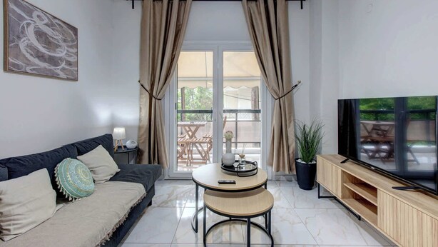 A modern living room with a sofa, TV, and a small table with a lamp. - Fresh 1 Bd Apartment with Balcony in Thessaloniki (Thessaloniki)