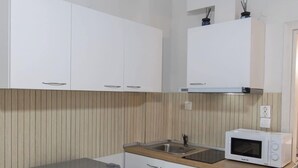 A compact kitchen with white cabinets, a stainless steel refrigerator, a microwave, and a wooden countertop. - Fresh 1 Bd Apartment with Balcony in Thessaloniki (Thessaloniki)
