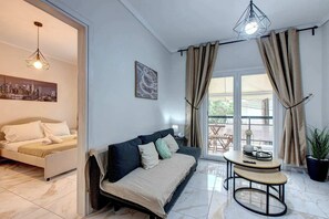 A modern living room with a sofa, a round table, and a cityscape painting. - Fresh 1 Bd Apartment with Balcony in Thessaloniki (Thessaloniki)