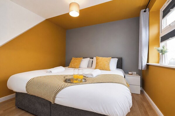 A bedroom with a bed, bedside table, and a window with curtains.