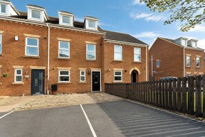 A residential building with a brick facade, multiple windows, and a gated driveway.