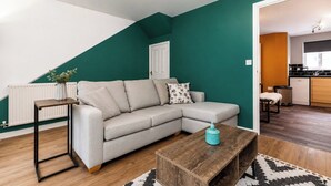Ein modernes Wohnzimmer mit einer Eckcouch, einem Couchtisch und Blick in den Küchenbereich.