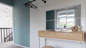 Una habitación con escritorio, silla, ventana y lámpara colgante.