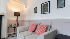Un dormitorio con cama, lámpara de pie y cuadros en la pared.