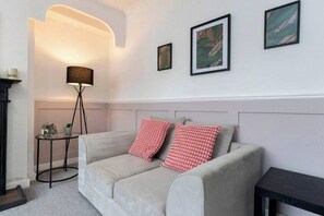 Ein Schlafzimmer mit einem Bett, einer Stehlampe und gerahmten Bildern an der Wand.