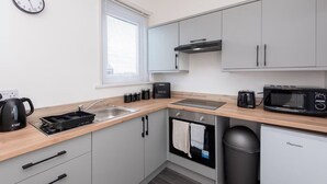 A compact kitchen with a sink, stove, microwave, toaster, and a small fridge. - *Discounts/Contractors/WIFI/Free Parking/Smart TV (Murton)
