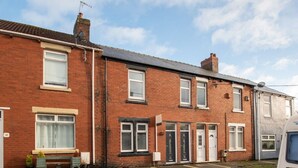 A row of terraced houses with front doors, windows, and a bench. - *Discounts/Contractors/WIFI/Free Parking/Smart TV (Murton)