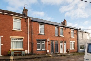 A row of terraced houses with front doors, windows, and a bench. - *Discounts/Contractors/WIFI/Free Parking/Smart TV (Murton)
