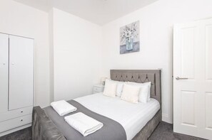 Ein Schlafzimmer mit einem Bett, Nachttischen, einem Kleiderschrank und einem Bild an der Wand.