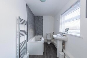 A modern bathroom with a bathtub, toilet, and sink. - *Discounts/Contractors/WIFI/Free Parking/Smart TV (Murton)