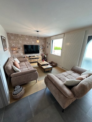 A modern living room with a sofa set, a TV, and a coffee table. - Entre Terre et Mer Maion family 12/14 persons with heated pool and dome (Landivisiau)