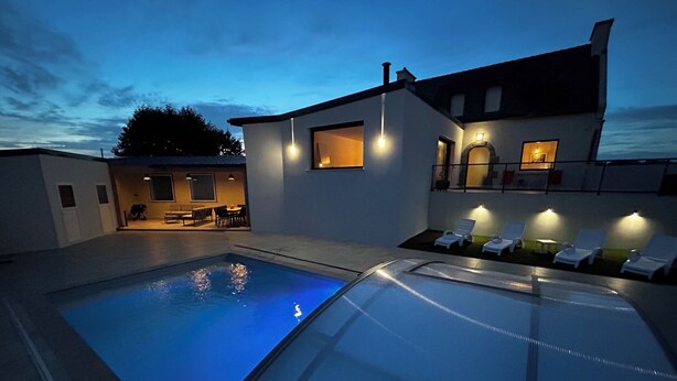 Une piscine avec des chaises longues et un bâtiment doté d’un balcon.